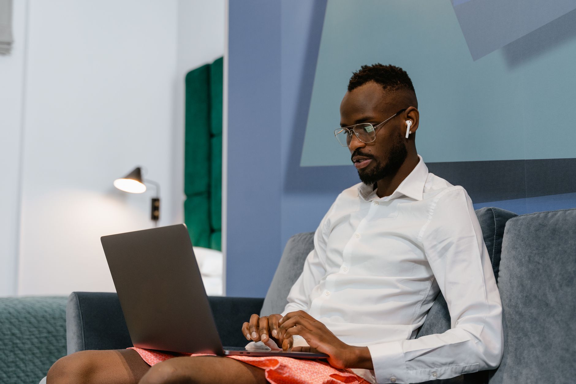 Man sitting on a sofa working remotely on a laptop at home.